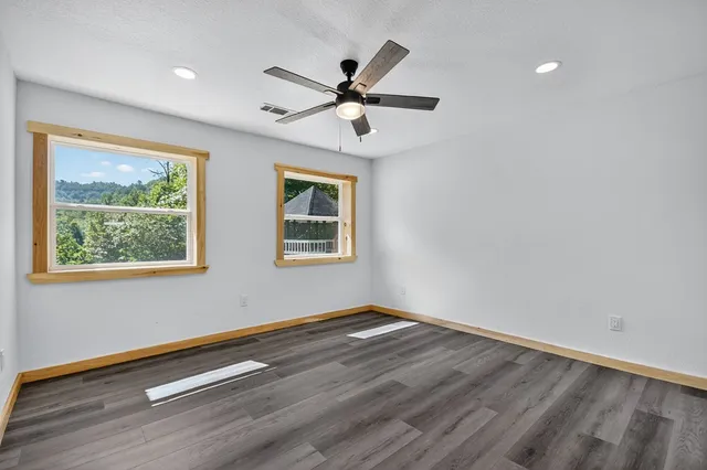 an empty room with wooden floor and windows