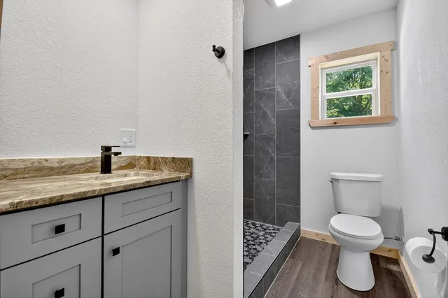 a bathroom with a toilet a sink a window and shower