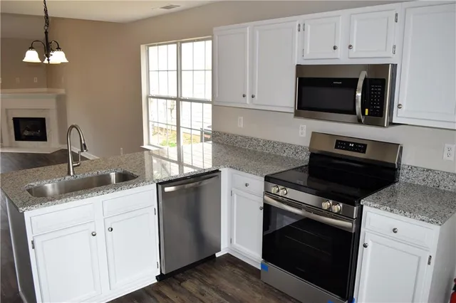 a kitchen with granite countertop a stove a sink and a microwave