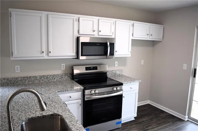 a kitchen with granite countertop white cabinets and stainless steel appliances