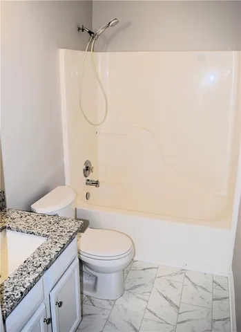 a bathroom with a granite countertop sink a toilet and a shower