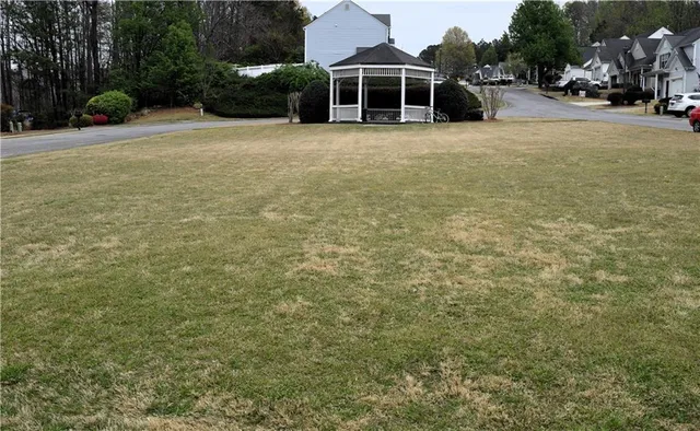 a view of a house with a yard and large trees