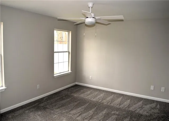 an empty room with a window and ceiling fan
