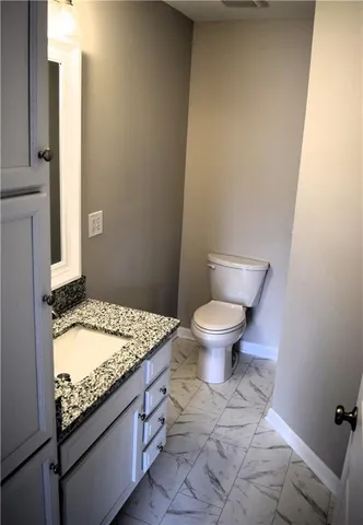 a bathroom with a granite countertop toilet and a sink