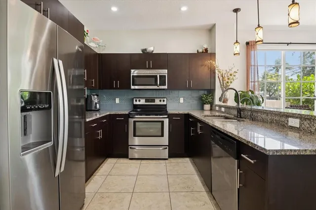 a kitchen with stainless steel appliances granite countertop a refrigerator a stove a sink and a microwave