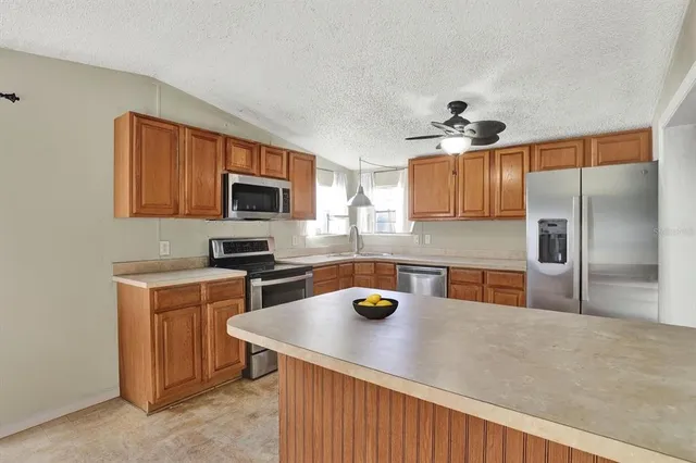 a kitchen with a refrigerator a stove a sink a counter top space and cabinets