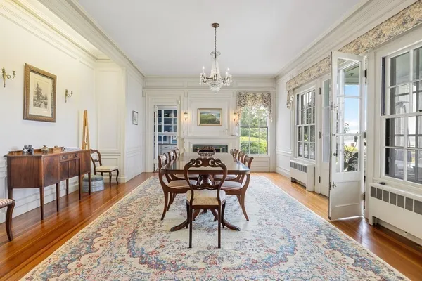 a dining room with wooden floor a chandelier a wooden table and chairs