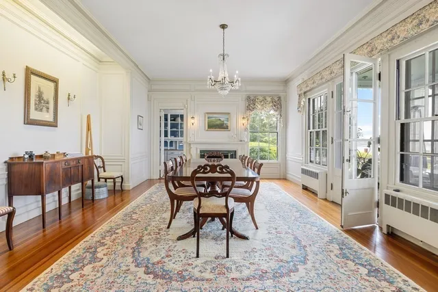 a dining room with wooden floor a chandelier a wooden table and chairs