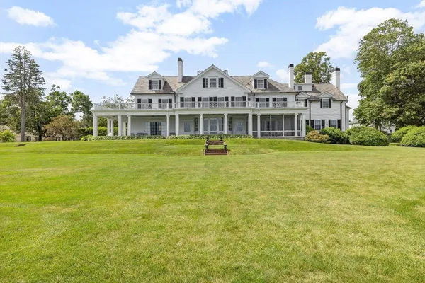 a front view of a house with a garden and lake view