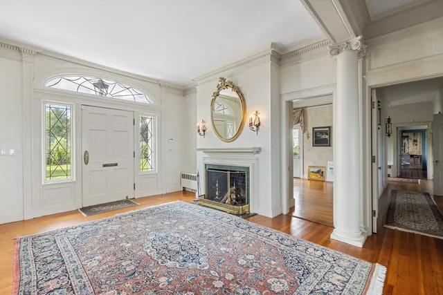 a view of an empty room with wooden floor fireplace and a window