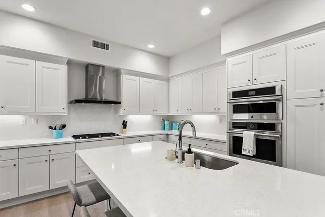 a kitchen with stainless steel appliances kitchen island a sink a stove and cabinets