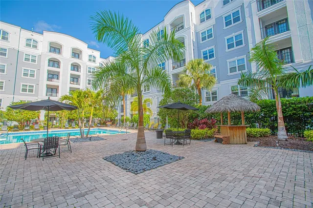 a front view of multi story residential apartment building with yard and bench