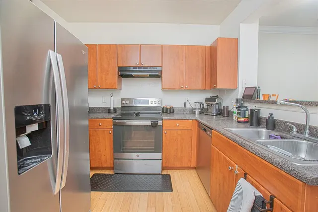 a kitchen with stainless steel appliances granite countertop a refrigerator a stove and a sink