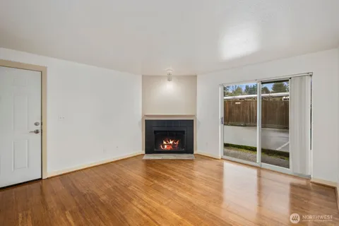 an empty room with wooden floor fireplace and windows