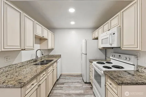 a kitchen with granite countertop a sink stove and refrigerator