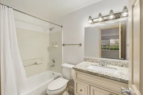a bathroom with a granite countertop sink toilet and shower