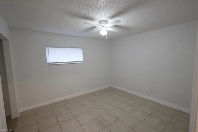 an empty room with white cabinet and windows
