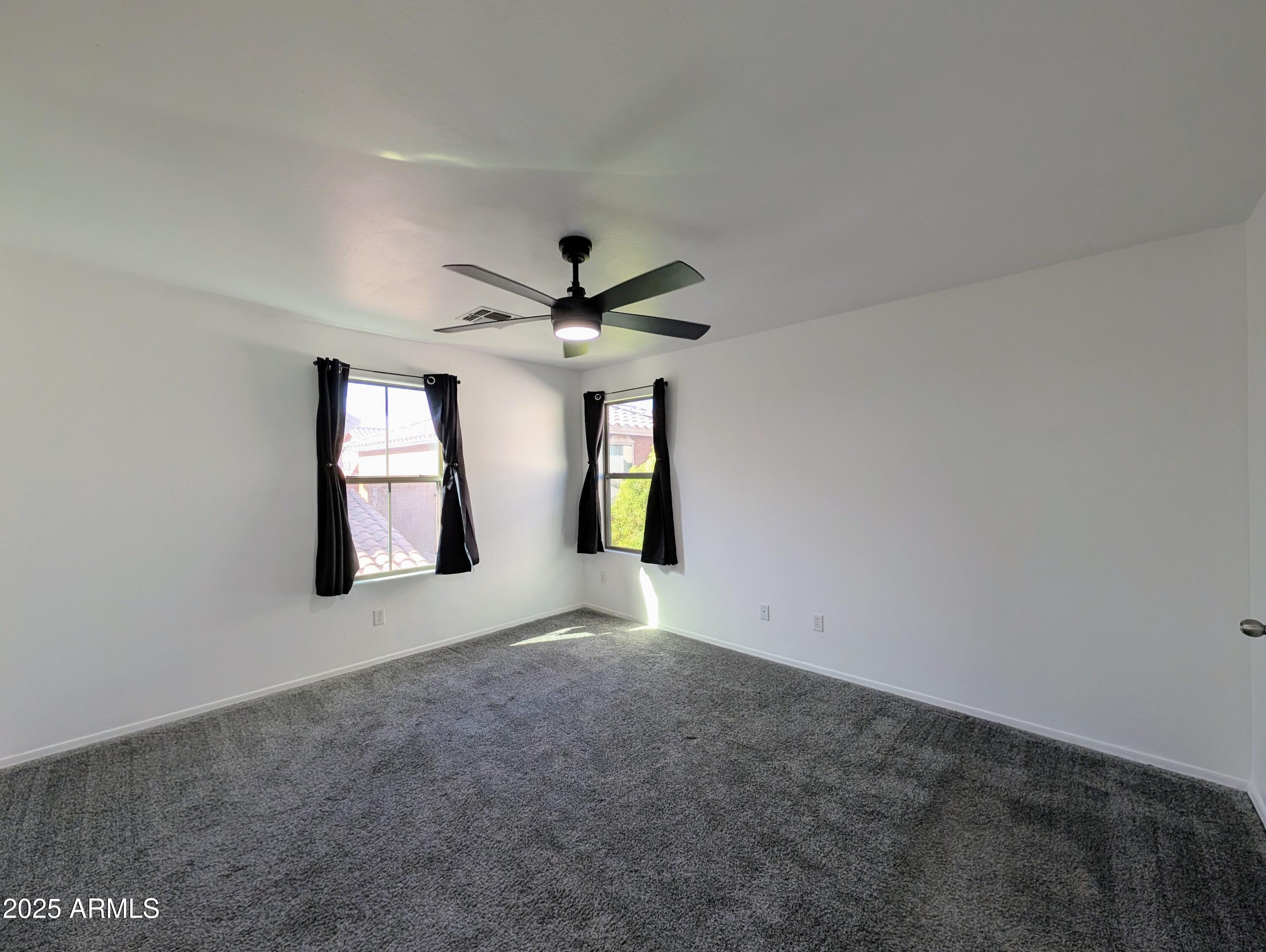 4726 West Fremont Rd. Laveen, AZ 85339 - Photo 29 of 50 an empty room with a chandelier fan and windows