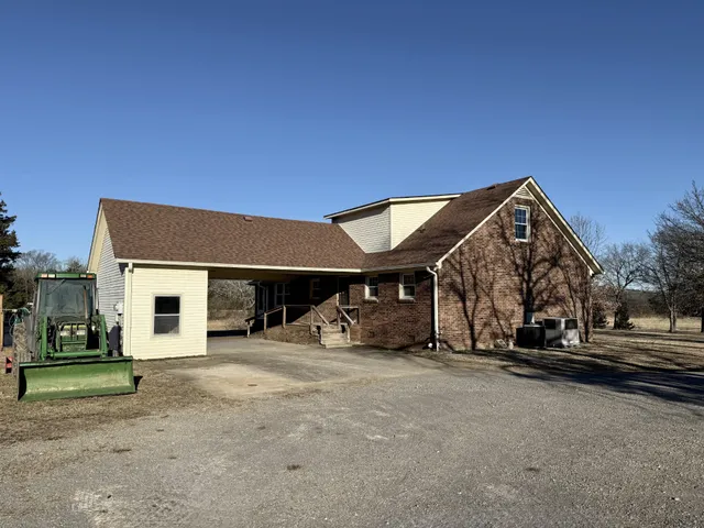 a view of a house with large trees and wooden fence