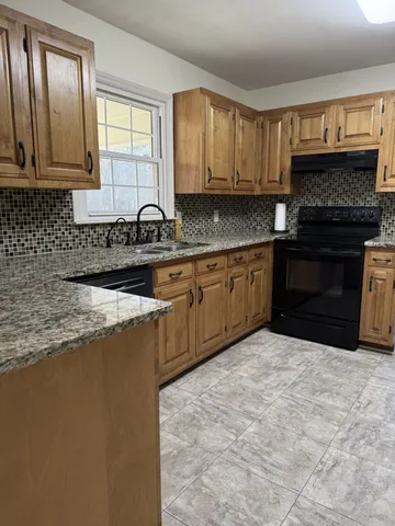 a kitchen with stainless steel appliances granite countertop a stove a sink and a microwave