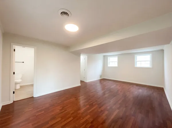 an empty room with wooden floor and windows