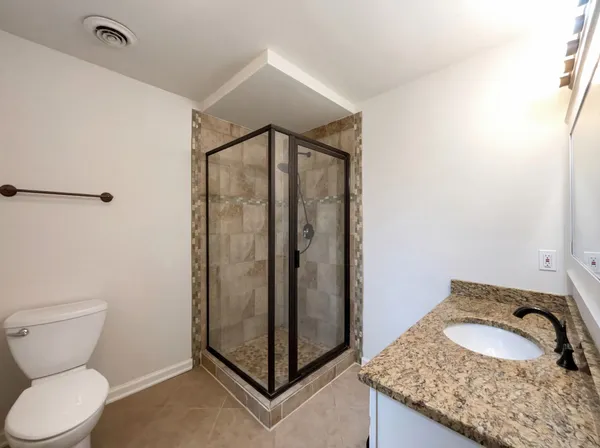 a bathroom with a granite countertop sink and a toilet