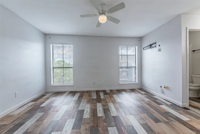 a view of a room with a ceiling fan window and wooden floor