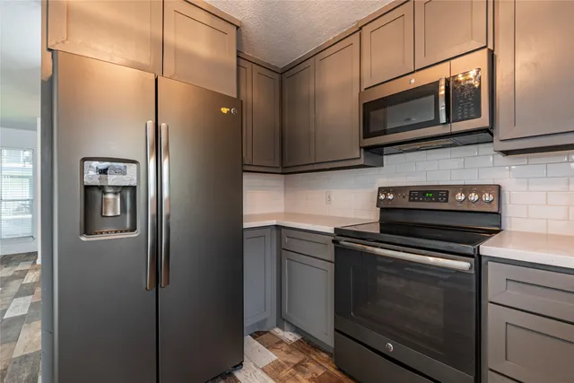 a kitchen with kitchen island granite countertop stainless steel appliances cabinets a sink and a window