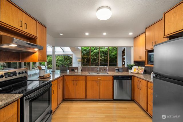 a kitchen with stainless steel appliances granite countertop a stove a sink and a refrigerator