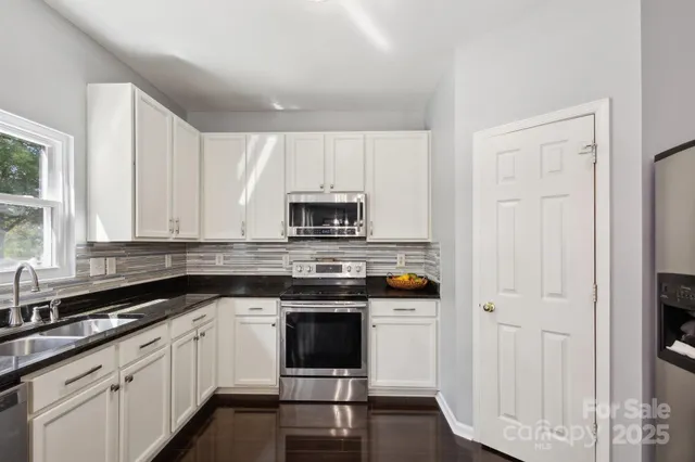 a kitchen with stainless steel appliances granite countertop a stove a sink and white cabinets