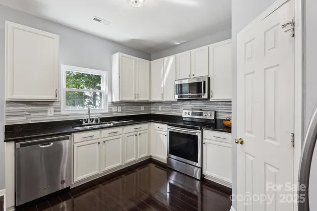a kitchen with granite countertop white cabinets and black stainless steel appliances