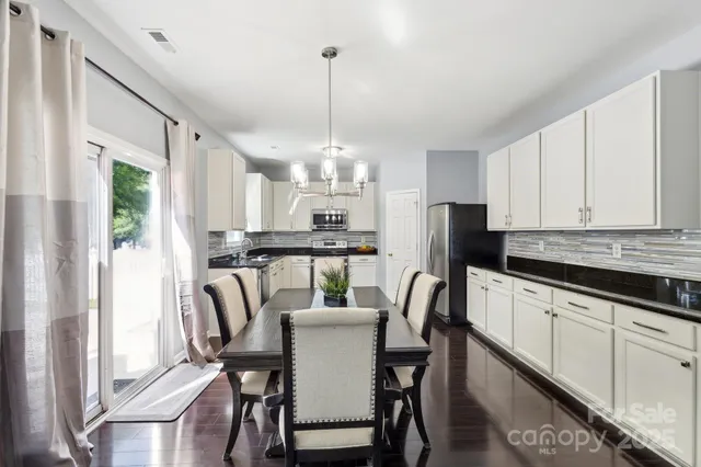 a kitchen with kitchen island a dining table chairs stainless steel appliances and cabinets