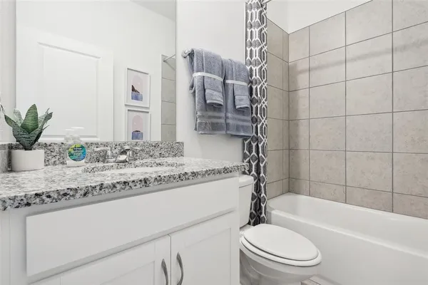 a bathroom with a granite countertop bathtub sink vanity mirror and toilet