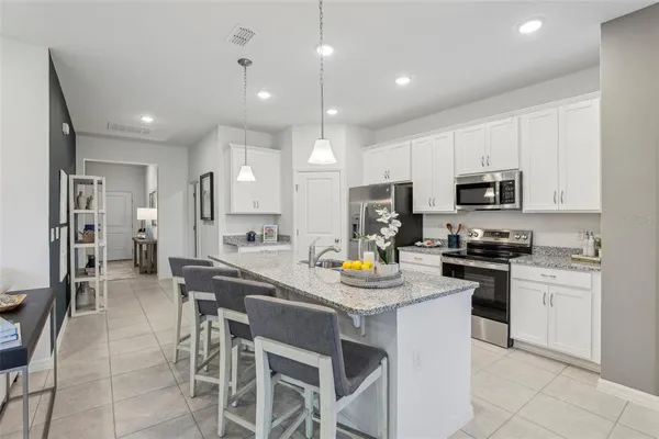 a kitchen with a dining table cabinets appliances and wooden floor