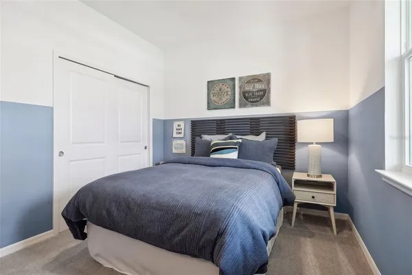 a bedroom with a bed and a lamp on the dresser