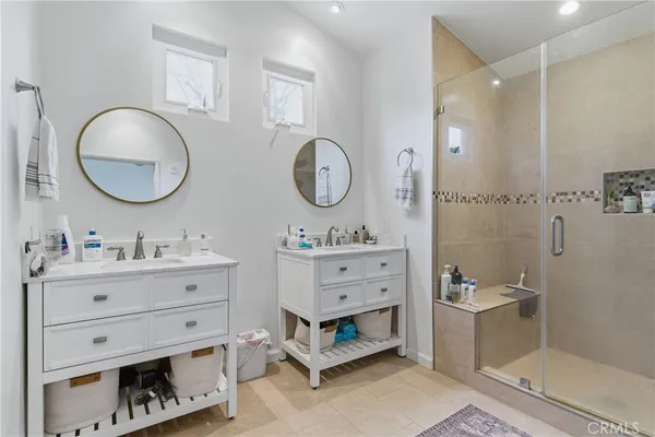 a bathroom with double vanity sink two mirror and a shower
