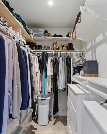 a view of walk in closet with clothes and shoes