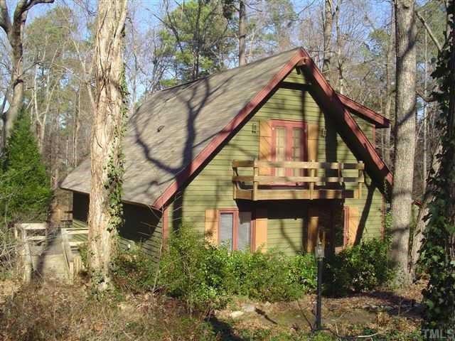 a view of a house with large trees and plants
