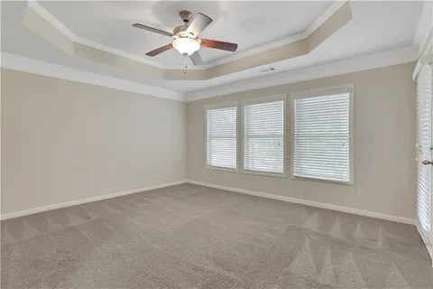 an empty room with chandelier fan and windows