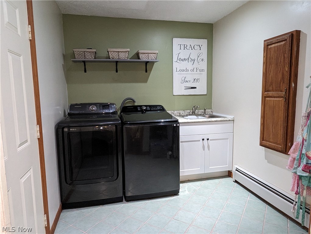 7272 Poore Road Conneaut, OH 44030 - Photo 13 of 26 Laundry area with cabinets, a baseboard heating unit, light tile floors, sink, and washing machine and dryer