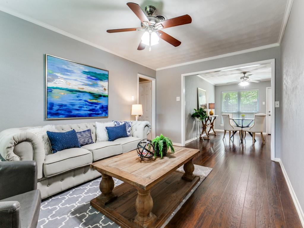 Living room featuring dark wood-style floors, ceiling fan, and crown molding
