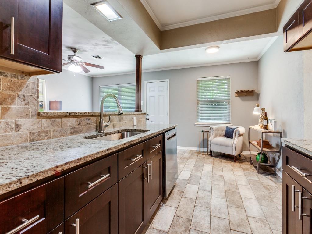 1106 Ridgeway Circle Richardson, TX 75080 - Photo 13 of 25 Kitchen with light stone countertops, dark wood finish cabinets, ceiling fan, decorative backsplash, and ornamental molding