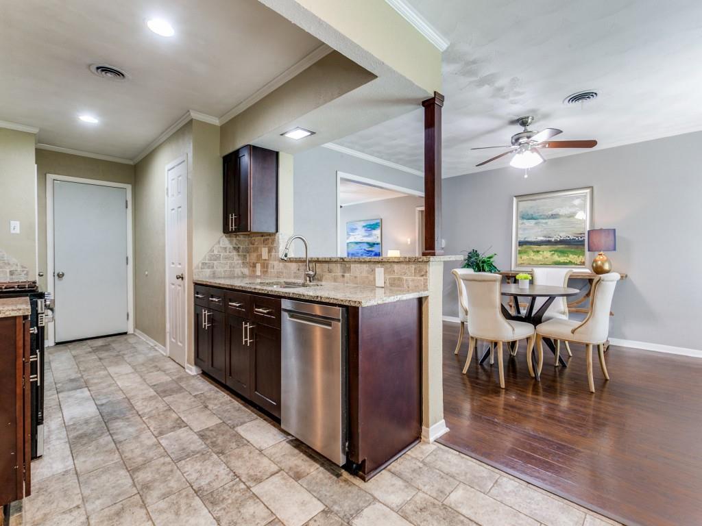 1106 Ridgeway Circle Richardson, TX 75080 - Photo 14 of 25 Kitchen featuring dark wood finish cabinets, light stone counters, stainless steel appliances, crown molding, and a peninsula
