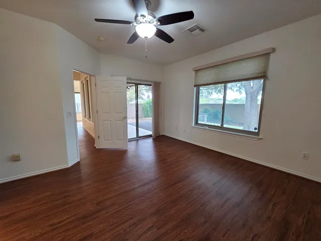 a view of an empty room with a window and wooden floor