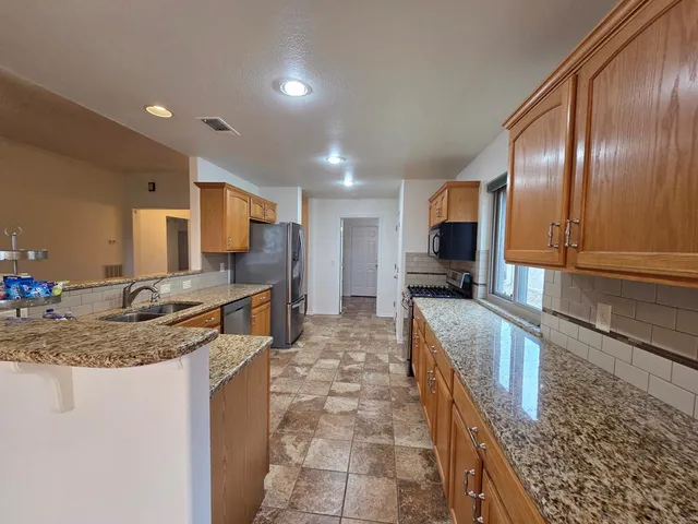 a large kitchen with kitchen island granite countertop a large counter top cabinets and stainless steel appliances