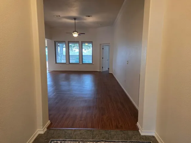 an empty room with wooden floor chandelier and windows