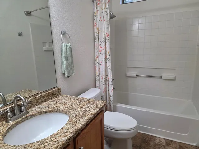 a bathroom with a granite countertop sink toilet and shower