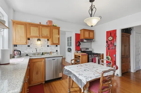 a kitchen with stainless steel appliances granite countertop a sink dishwasher and a refrigerator with wooden floor