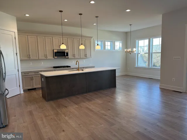 a large kitchen with stainless steel appliances granite countertop a sink a counter space and wooden floor