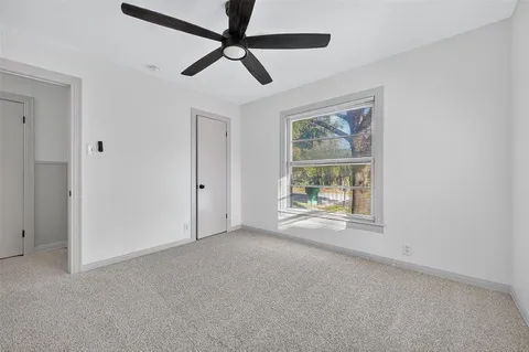 an empty room with window and ceiling fan